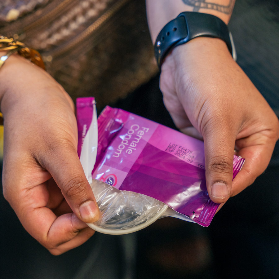 Photo of a person opening a packet containing a female condom